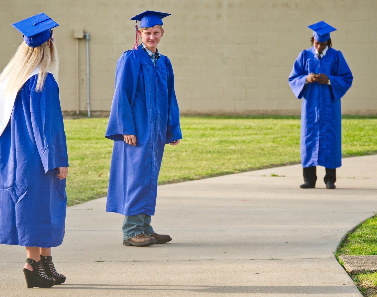Quitman seniors, from left, Savannah Breding, Larry Blankenship and Trey Berry keep appropriate distance Monday evening as they wait outside Bud Moody Stadium to walk for the school’s virtual graduation to be shown on May 22.
